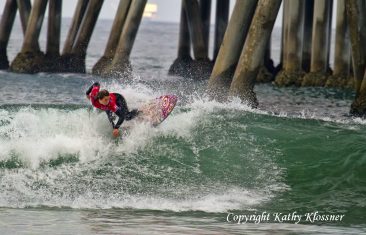 Tyler Wright banking off a wave next to the Huntington Beach pier