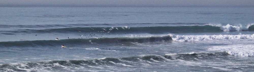 A crowd of surfers in the lineup on a big surf day.